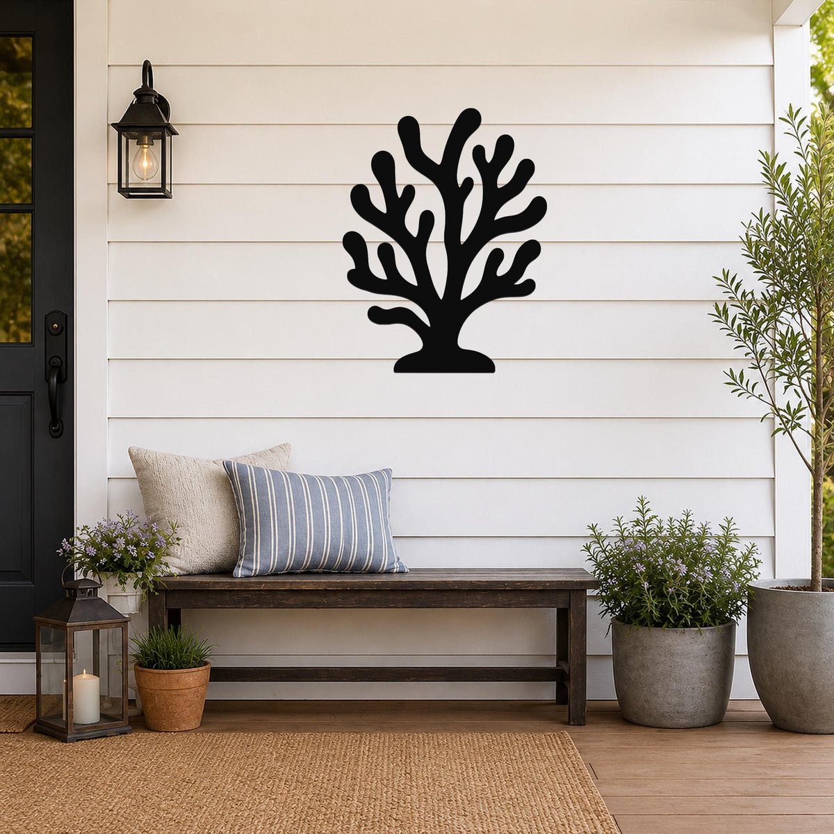 Black metal coral wall art with branching cutouts, mounted on a white shiplap wall above a wooden bench on a porch.