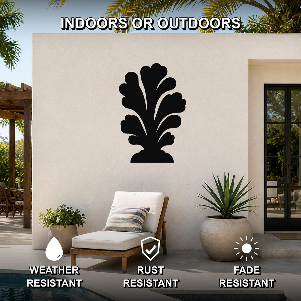 Black metal coral wall art with leafy cutout design, mounted on an outdoor patio wall above a lounge chair.