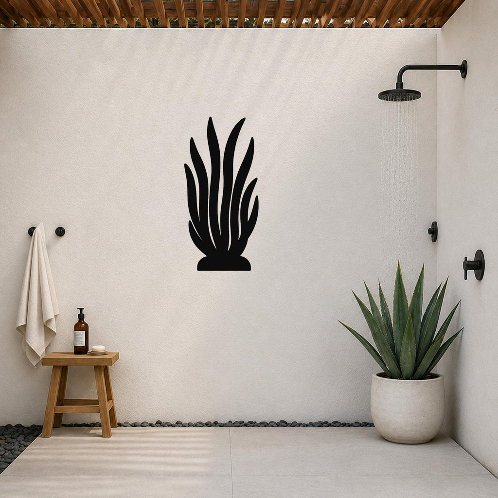 Black metal kelp wall art silhouette mounted on a white outdoor shower wall, with a potted succulent and shower fixtures visible nearby.