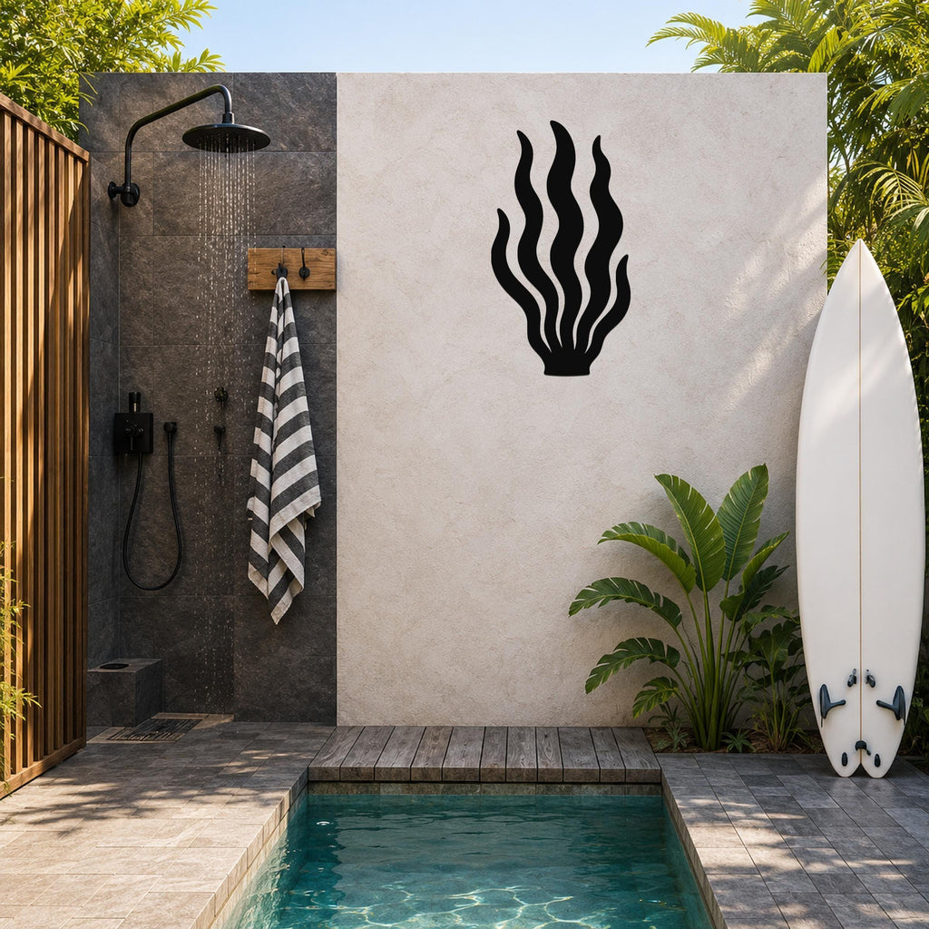 Black metal kelp wall art with flowing seaweed cutouts, mounted on a light-colored outdoor wall beside a shower and pool area.