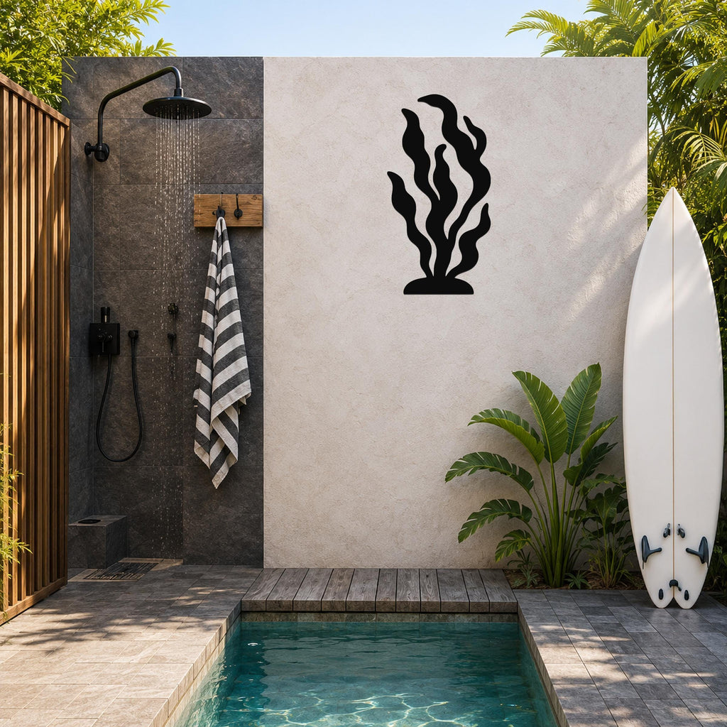 Black metal kelp wall art with flowing seaweed cutouts, mounted on a light-colored outdoor wall beside a shower and pool area.