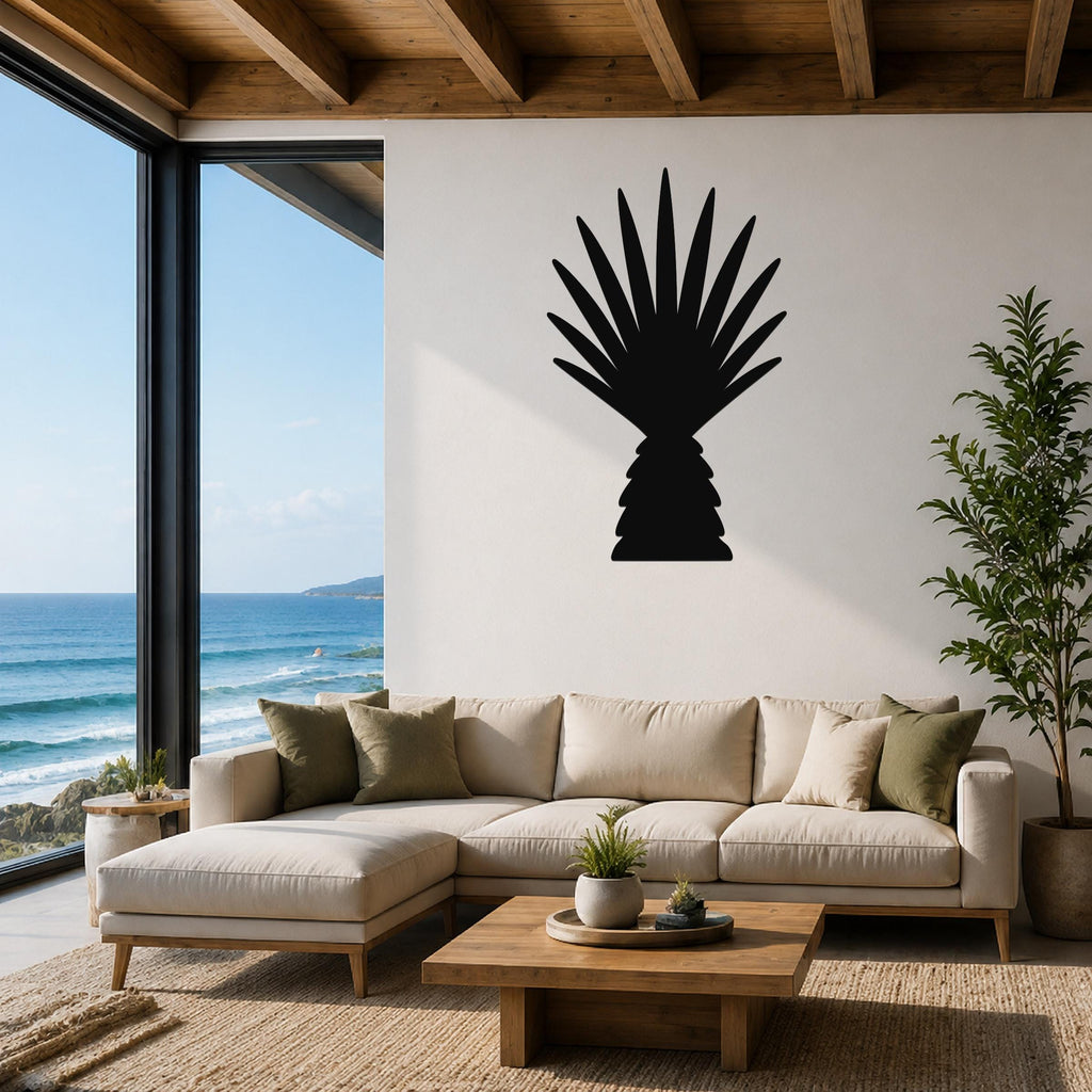 Black metal palm tree wall art with fan-shaped fronds, mounted on a white wall above a beige sectional sofa in a living room with ocean views.
