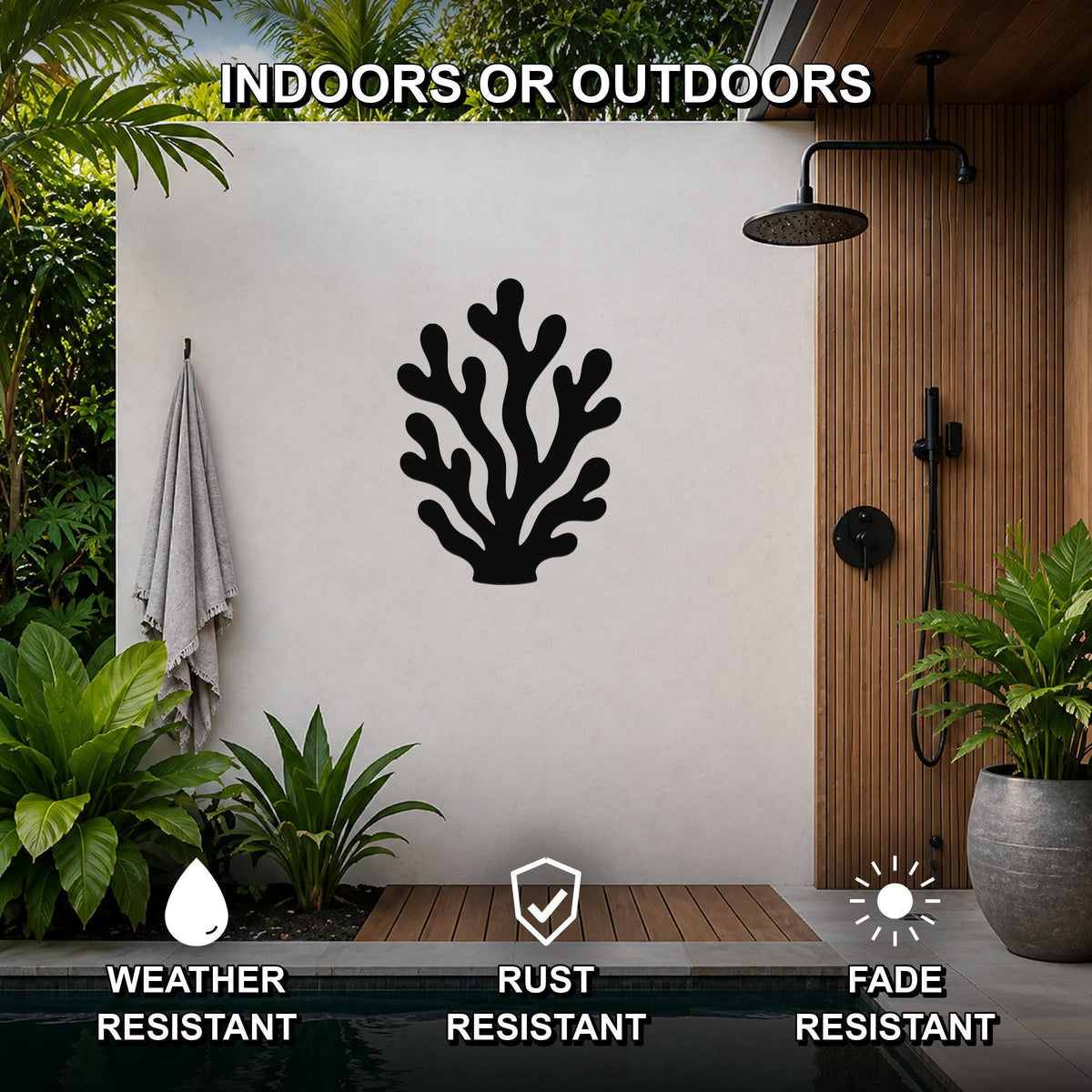 Black metal coral wall art with branching cutouts, mounted on a white outdoor wall beside a shower and pool area.