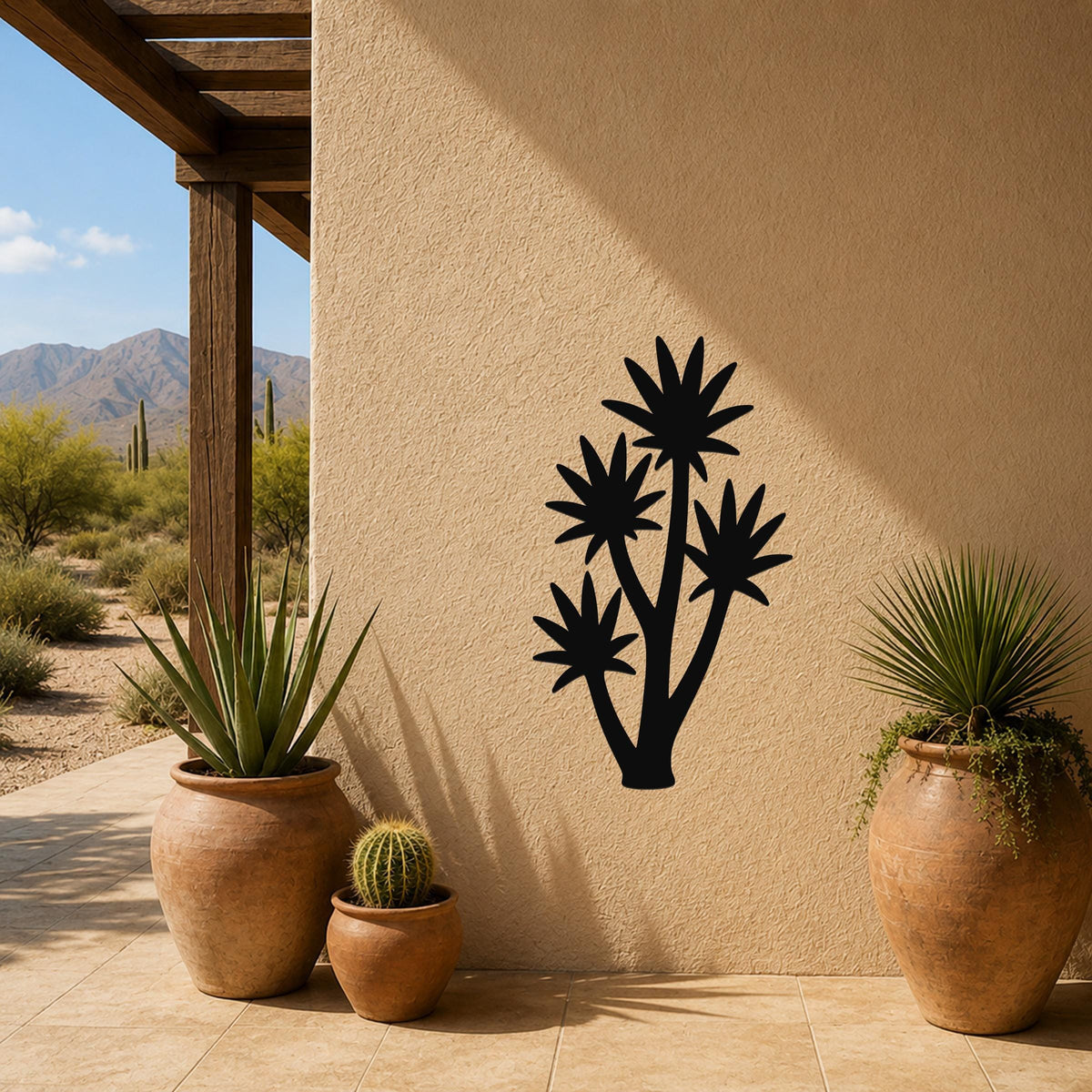 Black metal yucca wall art with multiple star-shaped leaf cutouts, mounted on a beige stucco outdoor wall beside potted plants on a patio.