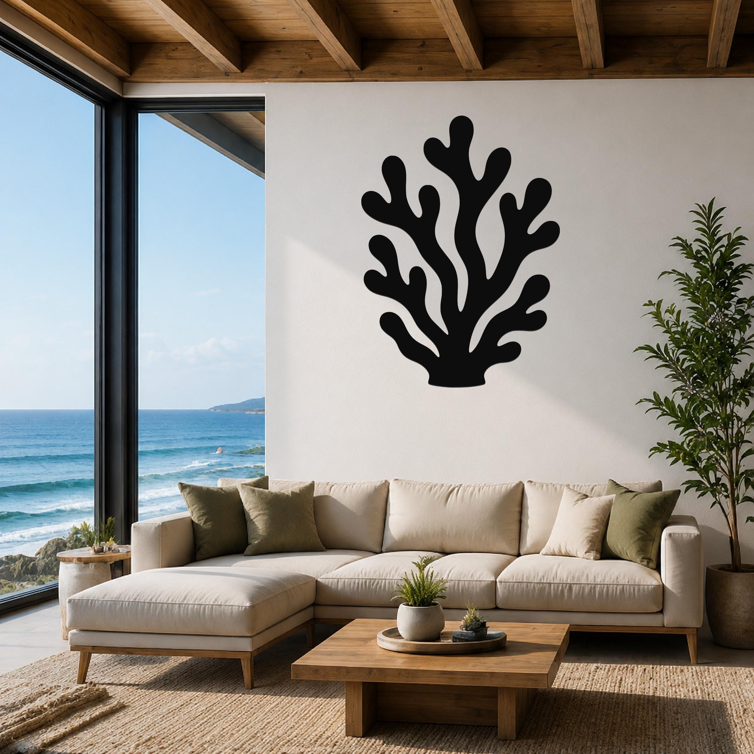 Black metal coral wall art with branching cutouts, mounted on a white living room wall above a beige sectional sofa.