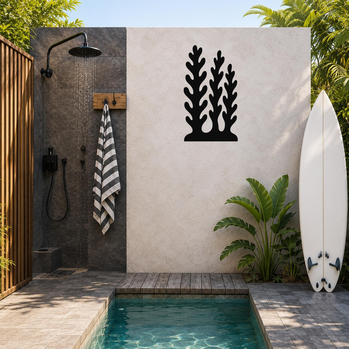 Black metal wall art with a kelp and seaweed silhouette design, mounted on a light-colored outdoor wall beside a shower and pool area.
