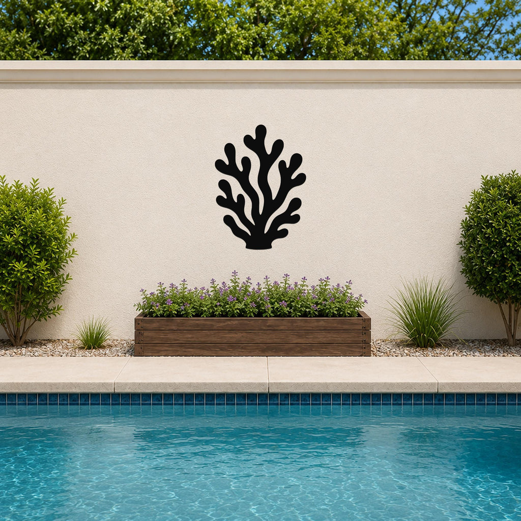 Black metal coral wall art with branching cutouts, mounted on an outdoor wall above a planter and pool.