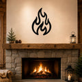 Black metal flame wall art with flowing, abstract cutout shapes, mounted above a stone fireplace in a rustic living room.