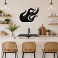 Black metal flame wall art with flowing cutout design, mounted on a kitchen wall above a counter with wicker bar stools.