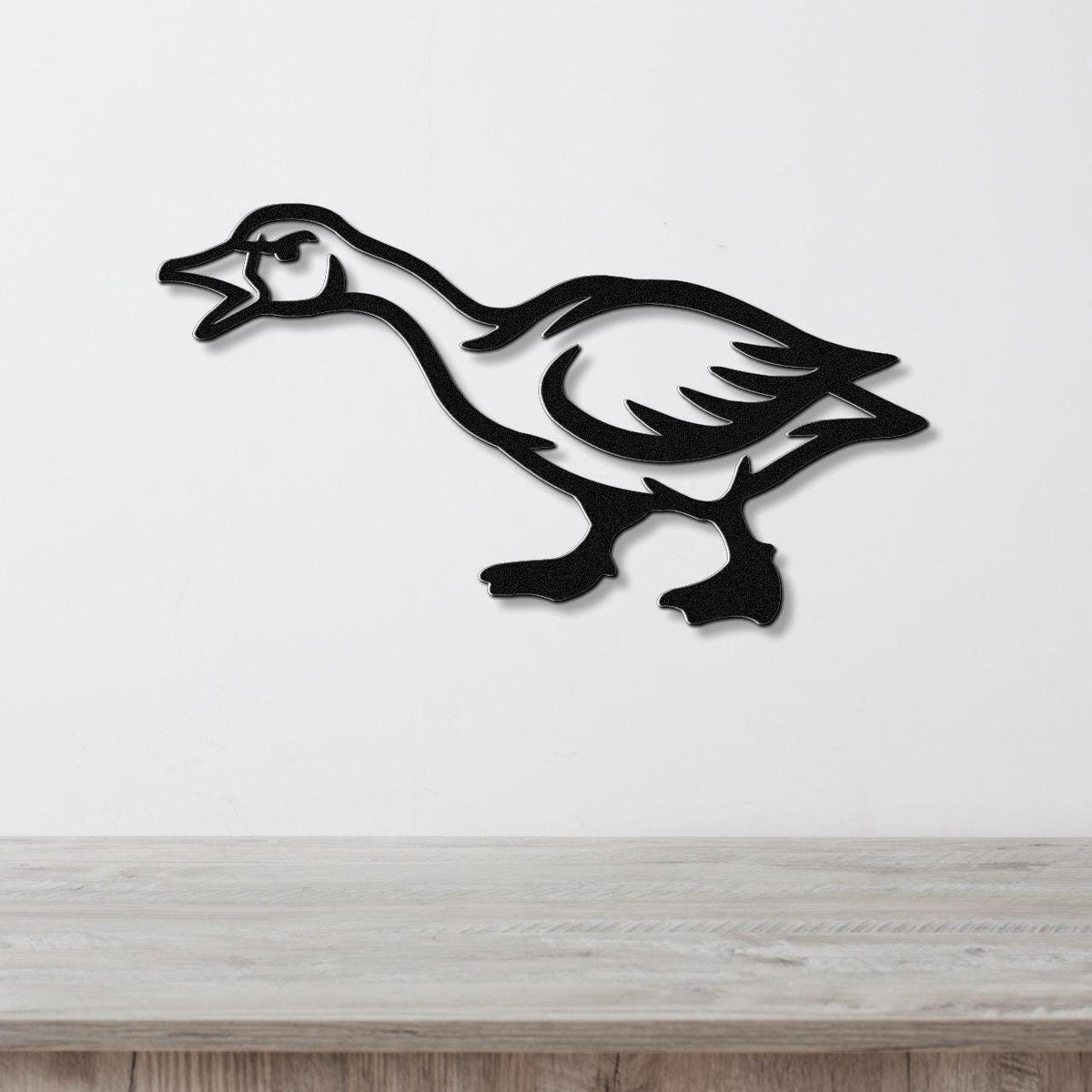Black metal goose wall art with a silhouette cutout design, mounted on a white wall above a light wood countertop.
