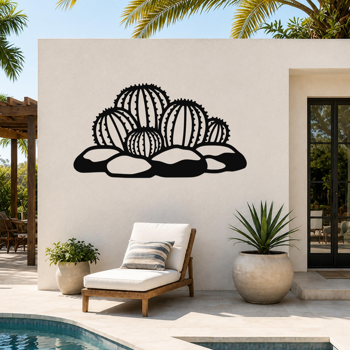 Black metal barrel cactus wall art with detailed spine cutouts, mounted on a white outdoor wall above a lounge chair near a pool.
