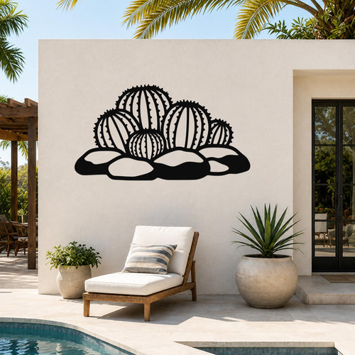 Black metal barrel cactus wall art with detailed spine cutouts, mounted on a white outdoor wall above a lounge chair near a pool.
