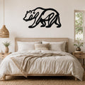 Black metal bear wall art with a star cutout, mounted above a wooden bed in a neutral bedroom.