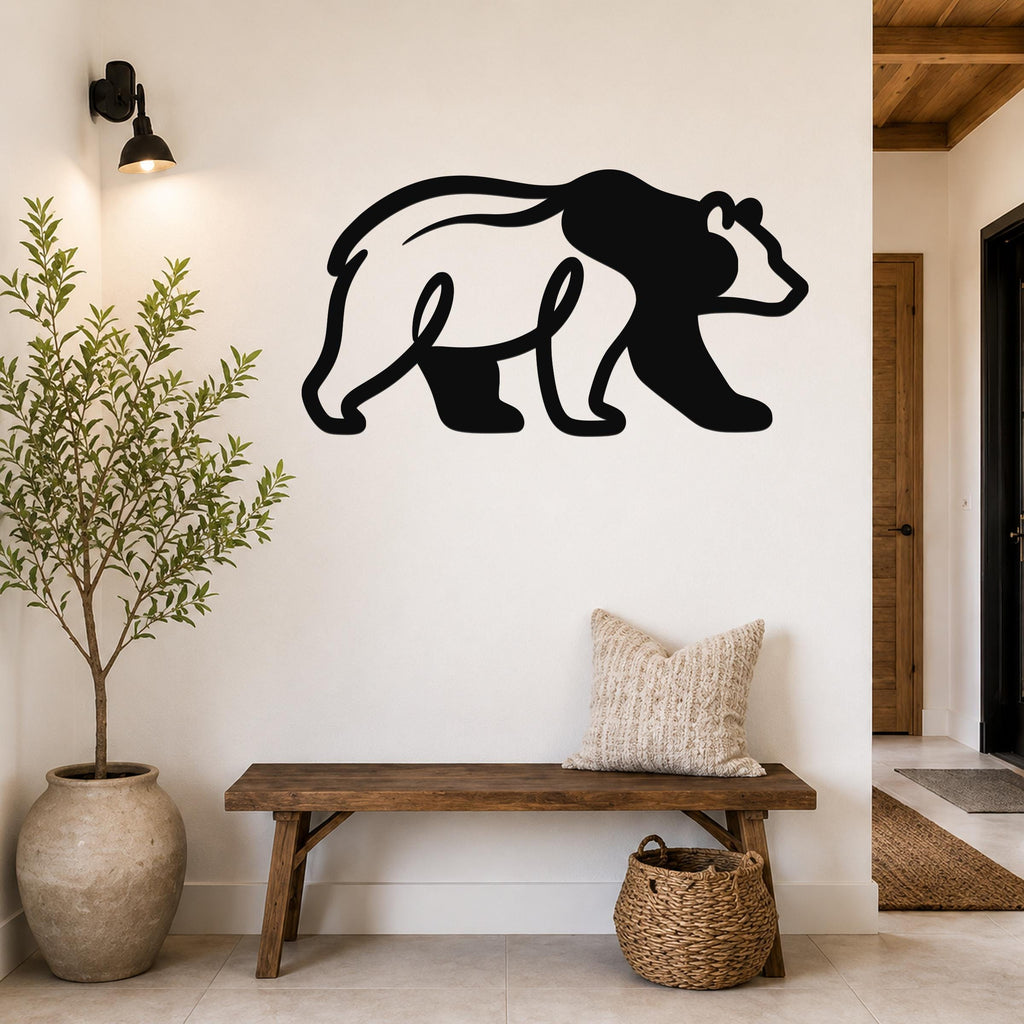 Black metal bear wall art silhouette mounted on a white wall above a wooden bench in a rustic entryway.