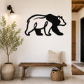 Black metal bear wall art silhouette mounted on a white wall above a wooden bench in a rustic entryway.