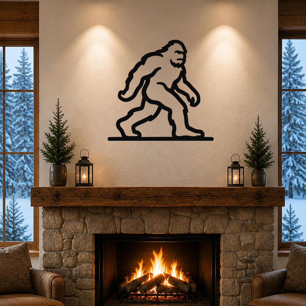 Black metal Bigfoot wall art silhouette mounted above a stone fireplace in a cozy living room with snow outside.