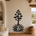 Black metal agave wall sculpture with blooming flower cutouts, mounted on a beige living room wall above a sofa.