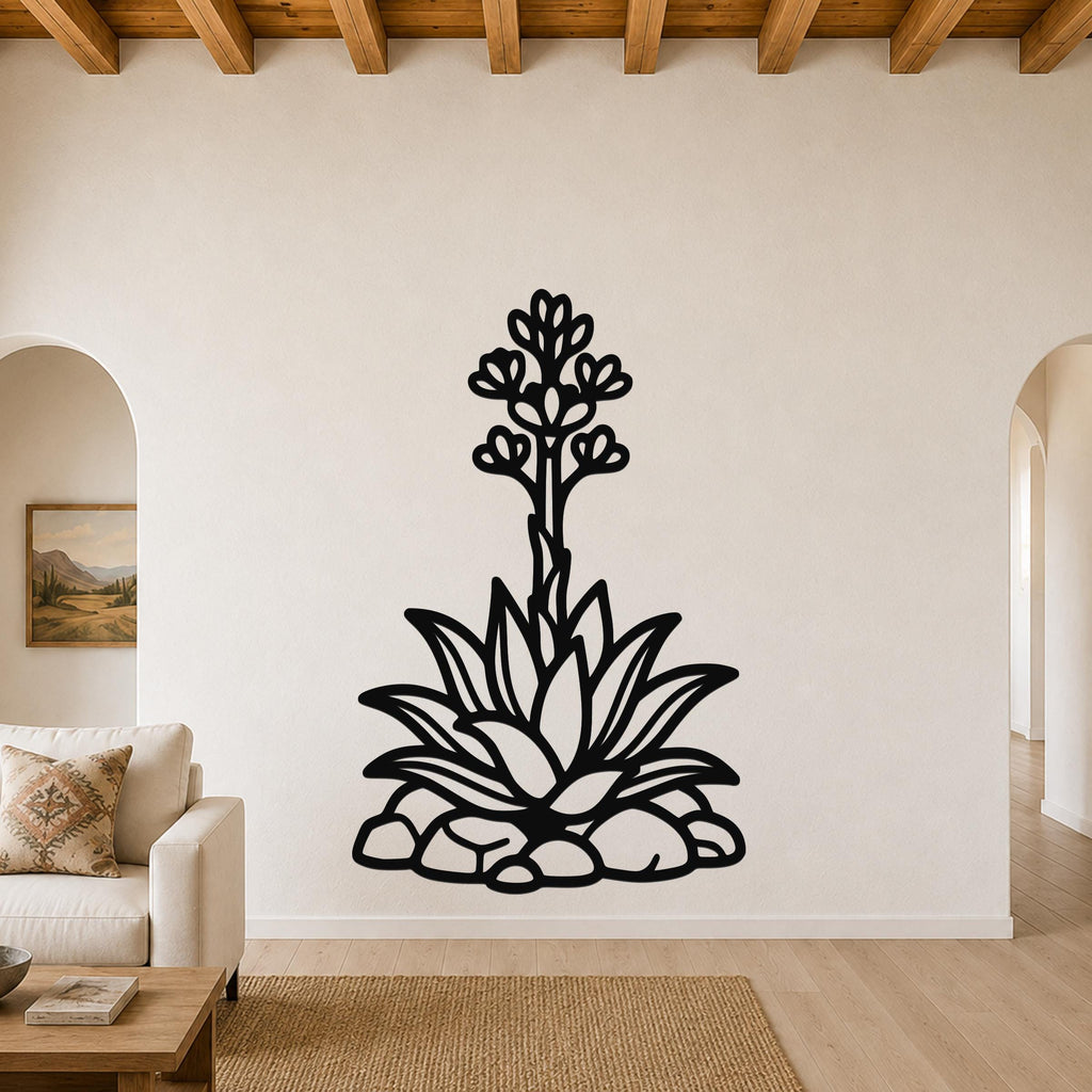 Black metal agave wall art with blooming flower and leaf cutouts, mounted on a living room wall above a sofa.