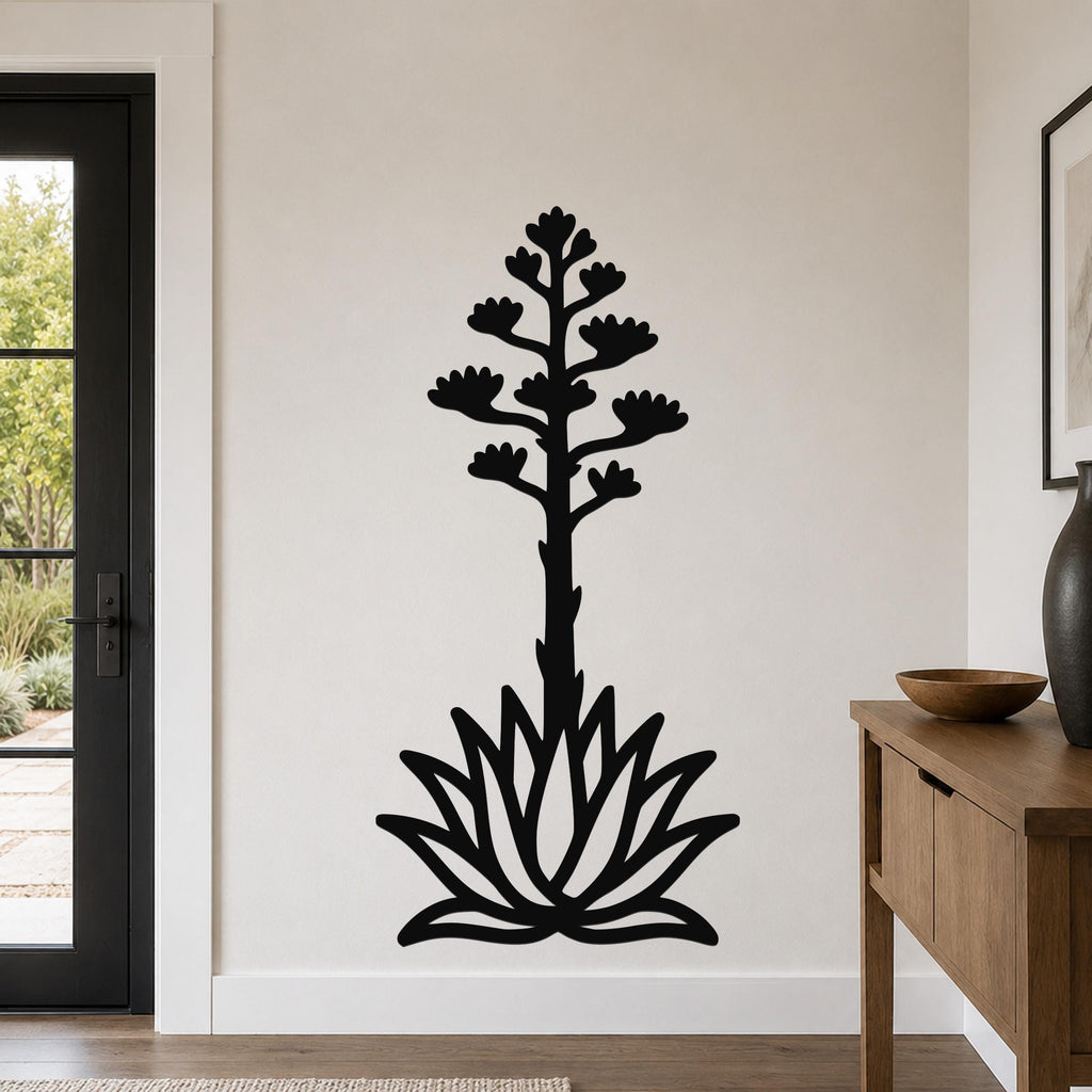 Black metal agave wall art with a blooming flower stalk and rosette cutouts, mounted on a light-colored wall in a living room.