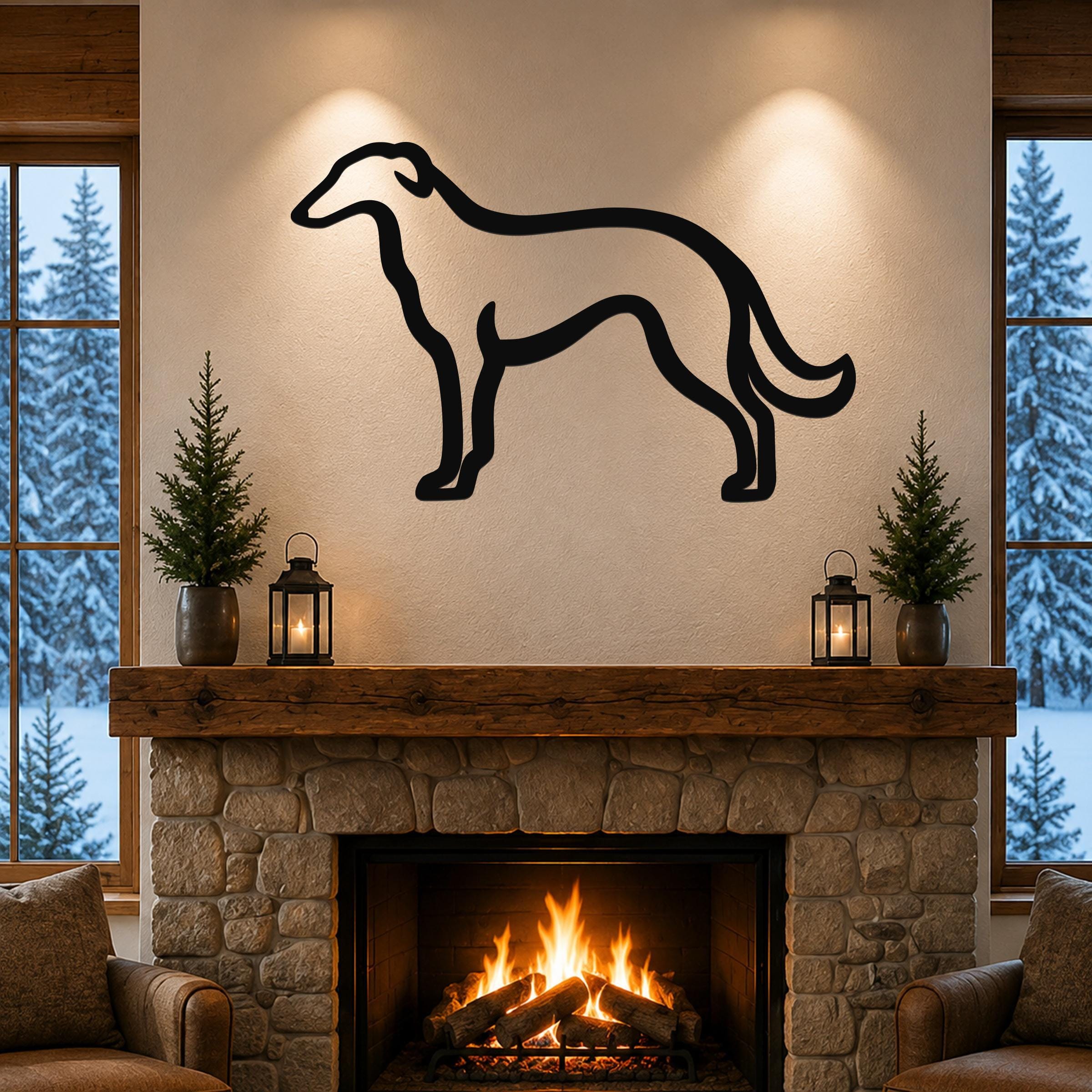 Black metal Borzoi dog silhouette wall art mounted above a stone fireplace in a cozy living room with snow outside the windows.