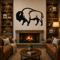 Black metal buffalo wall art silhouette mounted above a stone fireplace in a living room with leather sofas and wooden bookshelves.
