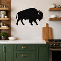 Black metal buffalo wall art silhouette mounted on a white tiled kitchen wall above a counter.