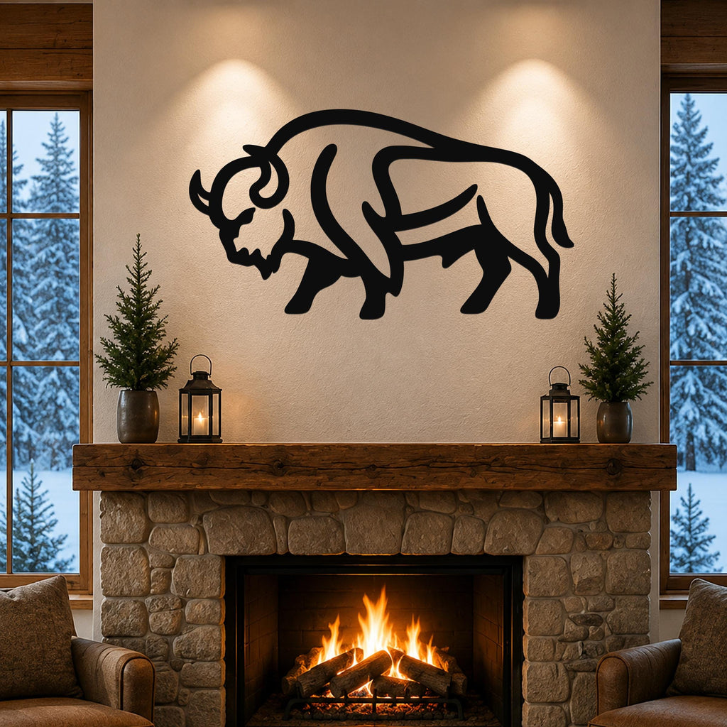 Black metal bison silhouette wall art mounted above a stone fireplace in a rustic living room with a snowy forest view.
