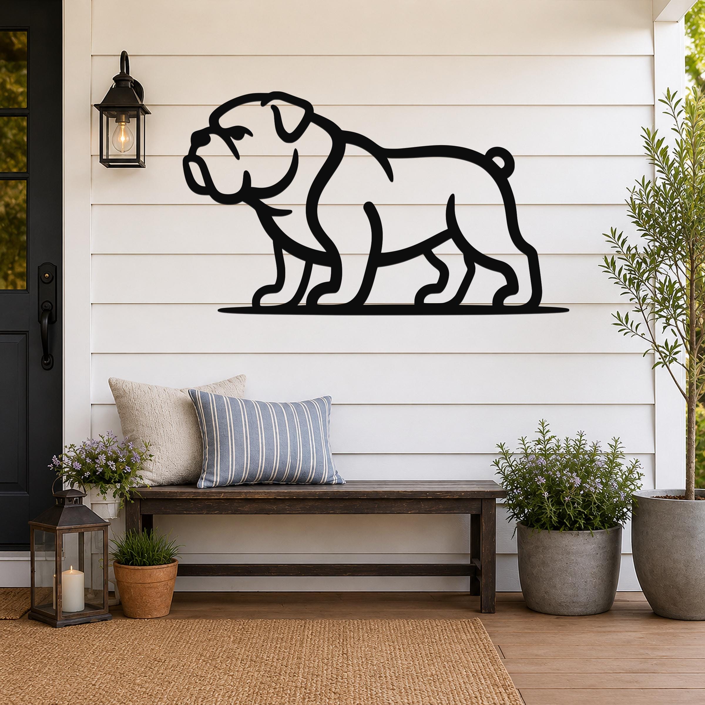 Black metal bulldog wall art silhouette mounted on a white shiplap wall above a wooden bench on a porch.