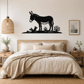 Black metal burro wall art silhouette with cactus and desert plants, mounted above a bed in a neutral bedroom.
