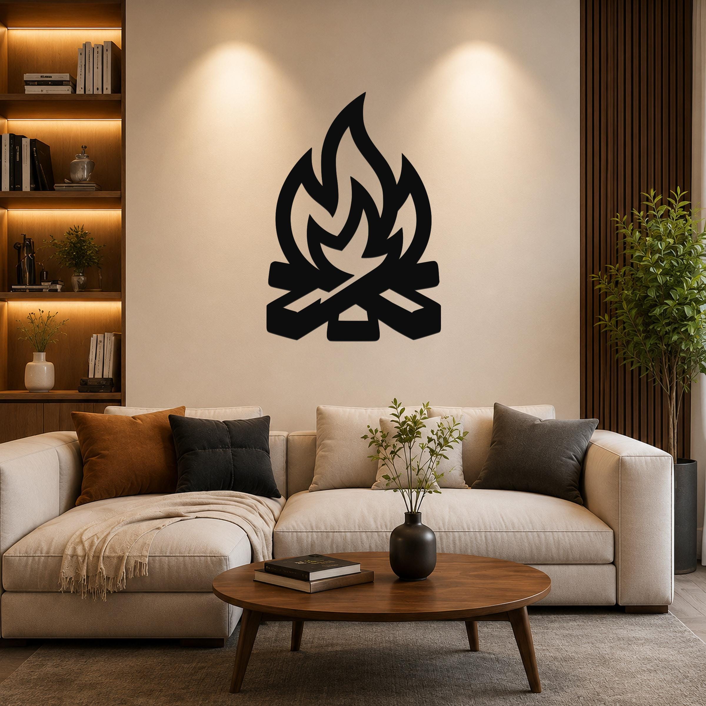 Black metal campfire wall art with flame and log silhouette, mounted on a living room wall above a beige sofa.