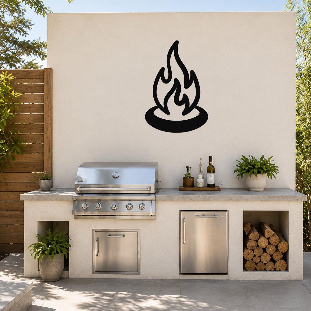 Black metal campfire silhouette wall art mounted on a light-colored outdoor wall above a stainless steel grill and countertop.