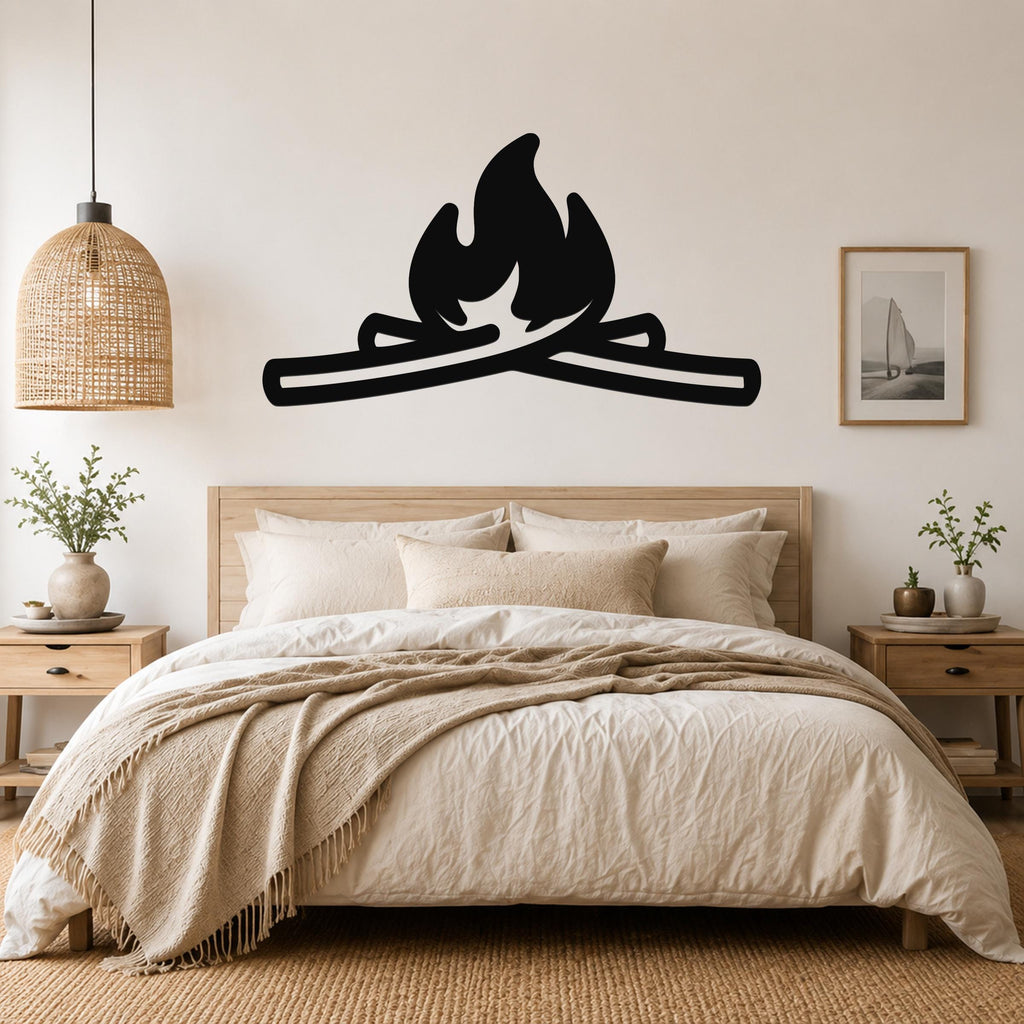 Black metal campfire wall art with flame and log silhouette, mounted above a wooden bed in a neutral bedroom.