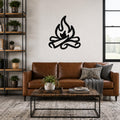 Black metal campfire wall art with flame and log silhouette, mounted above a brown leather sofa in a living room.