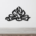 Black metal wall art with a flame and leaf cutout design, mounted on a white wall above a light wood counter.