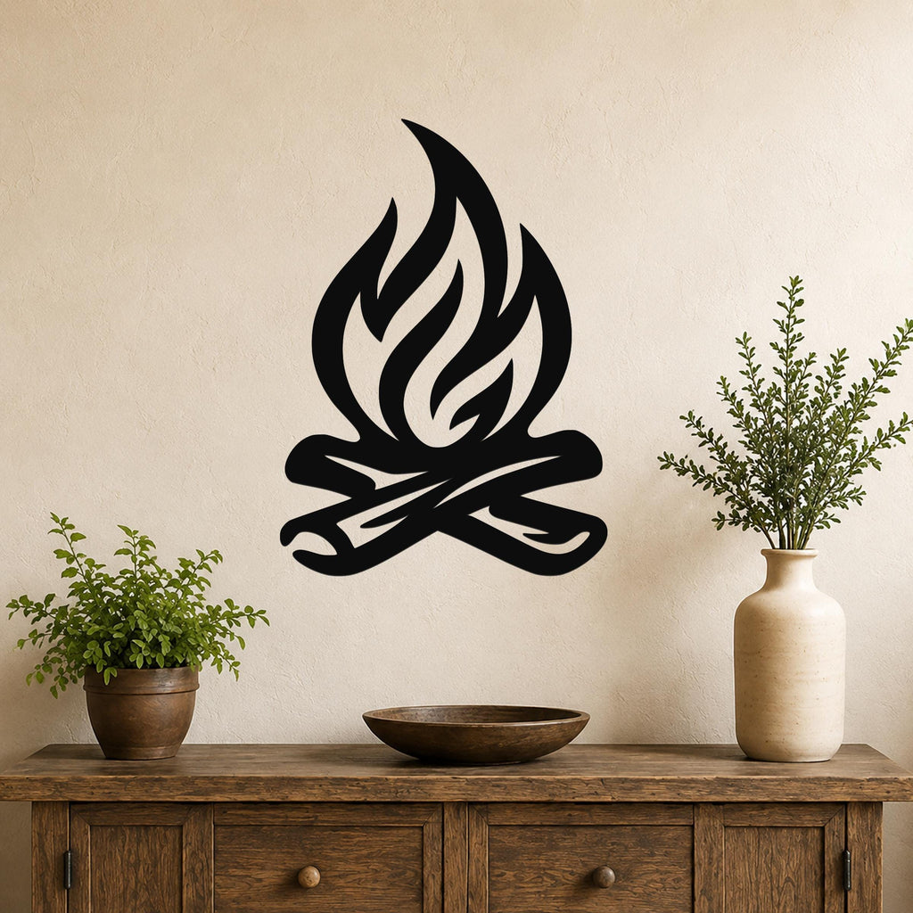Black metal campfire wall art with flame and log silhouette, mounted above a wooden console table in a living room with potted plants.