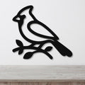 Black metal cardinal wall art silhouette perched on a branch, mounted on a white wall above a light wood counter.
