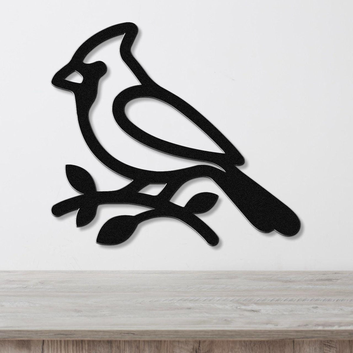 Black metal cardinal wall art silhouette perched on a branch, mounted on a white wall above a light wood counter.