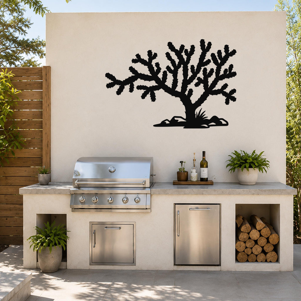 Black metal Cholla cactus wall art silhouette mounted on an outdoor kitchen wall above a stainless steel grill and counter.