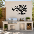Black metal Cholla cactus wall art silhouette mounted on an outdoor kitchen wall above a stainless steel grill and counter.