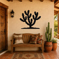 Black metal Cholla cactus wall art silhouette mounted on a stucco wall above a wooden bench in a patio entryway.