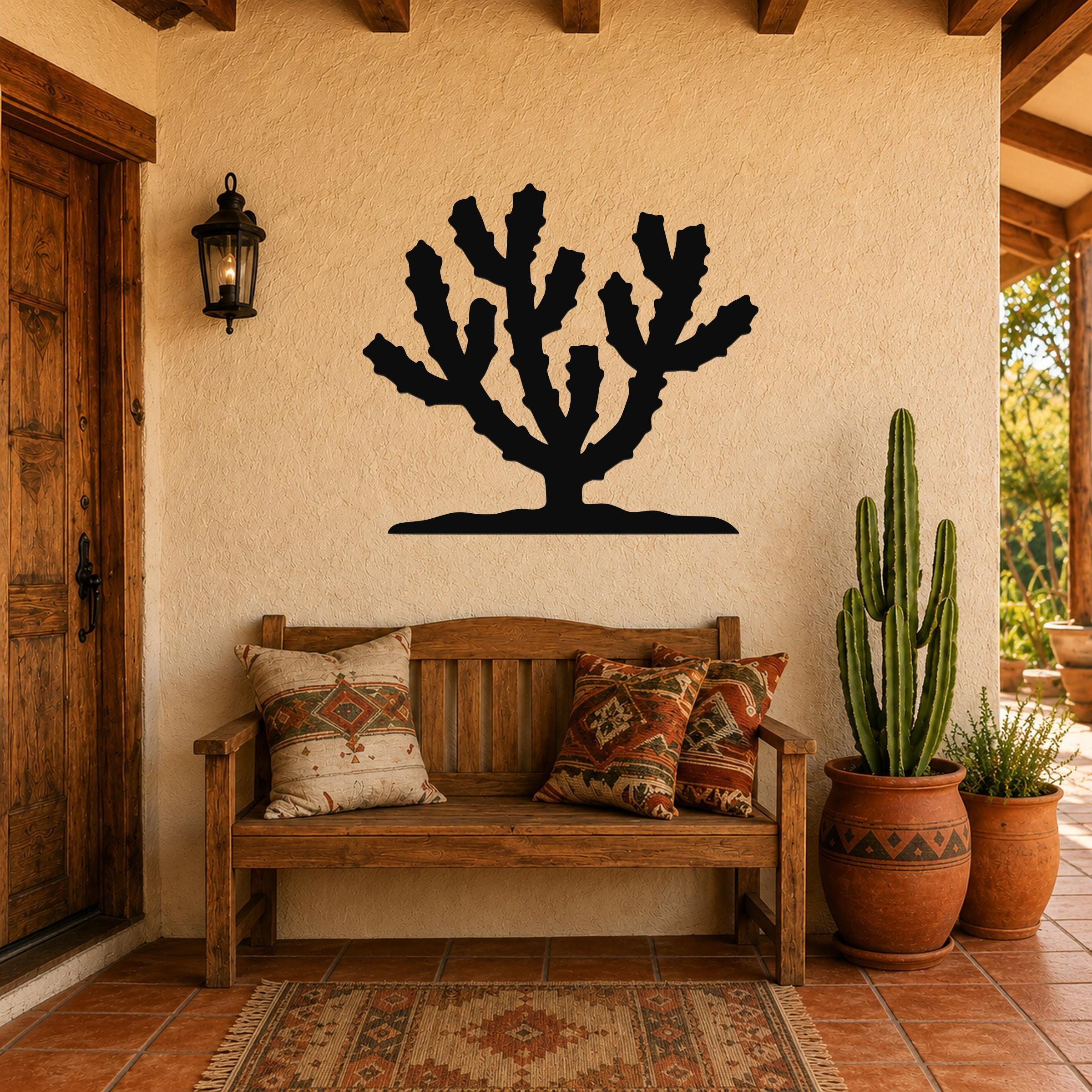 Black metal Cholla cactus wall art silhouette mounted on a stucco wall above a wooden bench in a patio entryway.