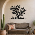 Black metal Cholla cactus wall art with spiky branch cutouts, mounted on a beige stucco wall above a wooden bench in a southwestern-style patio.