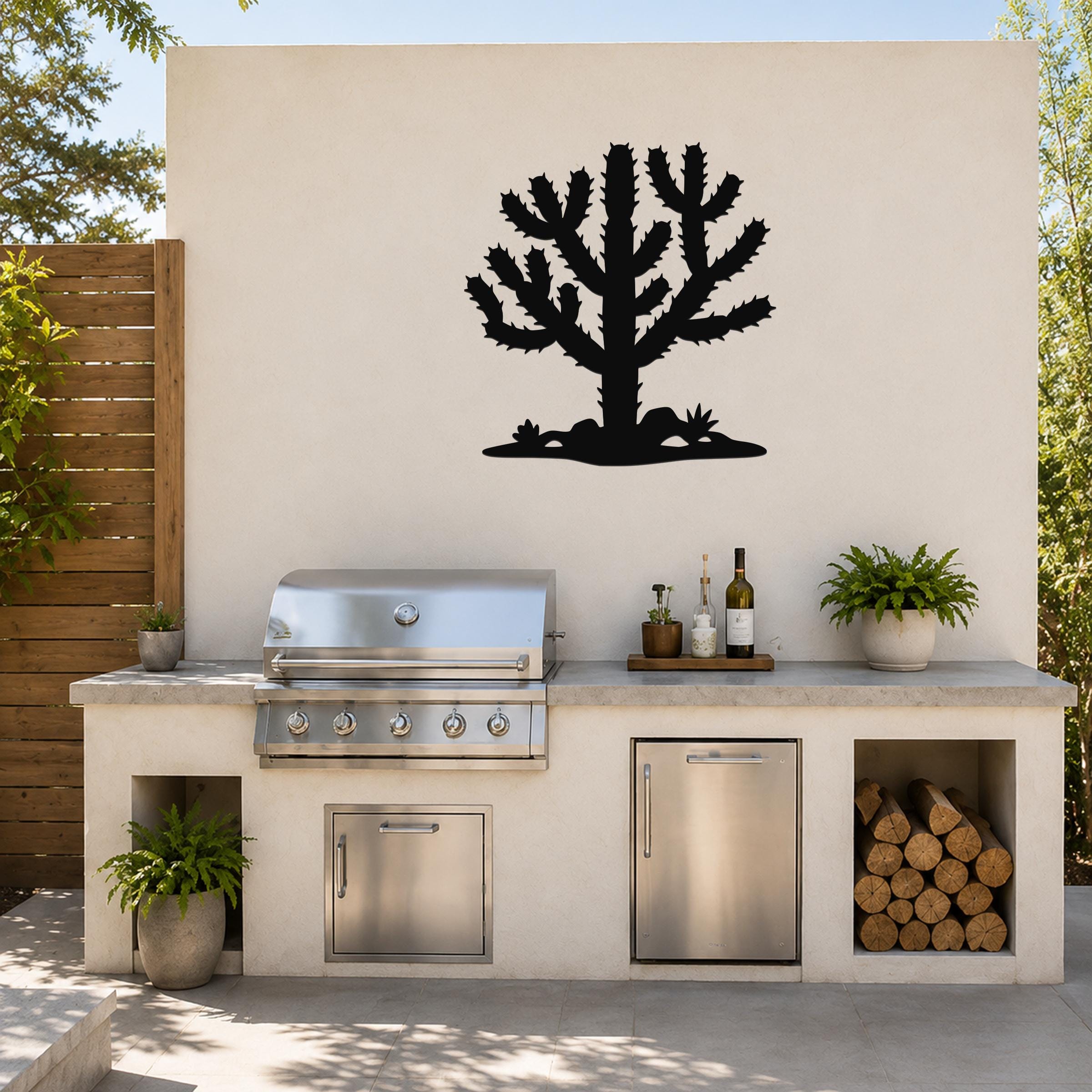 Black metal Cholla cactus wall art silhouette mounted on a beige outdoor wall above a built-in grill and counter.
