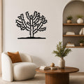 Black metal Cholla cactus wall art with branching silhouette, mounted on a living room wall above a white armchair.