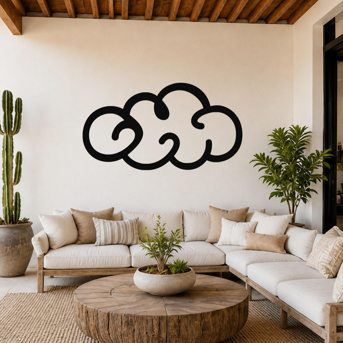Black metal cloud wall art with a bold silhouette design, mounted on a white wall above a white sofa in a living room.