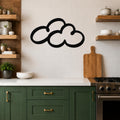 Black metal cloud wall art with a bold silhouette design, mounted on a tiled kitchen wall above a white countertop.