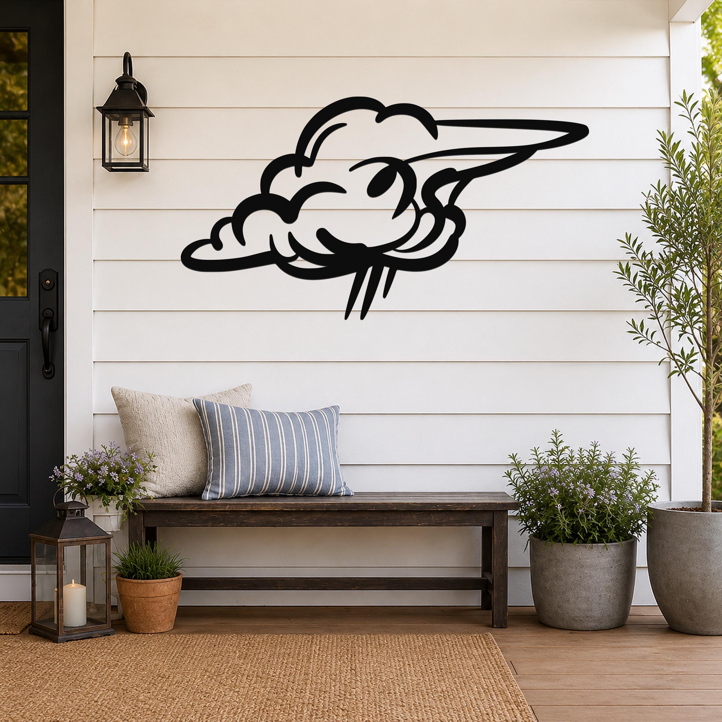 Black metal cloud wall art with a wavy, flowing silhouette, mounted on a white shiplap wall above a wooden bench on a porch.