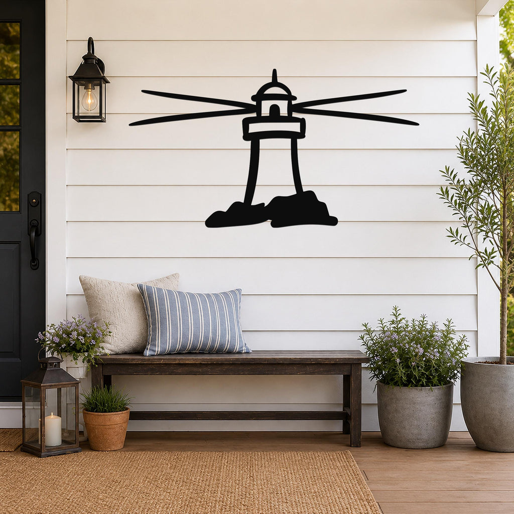 Black metal lighthouse wall art with motion-line cutouts, mounted on a white shiplap wall above a wooden bench on a porch.