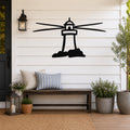 Black metal lighthouse wall art with motion-line cutouts, mounted on a white shiplap wall above a wooden bench on a porch.