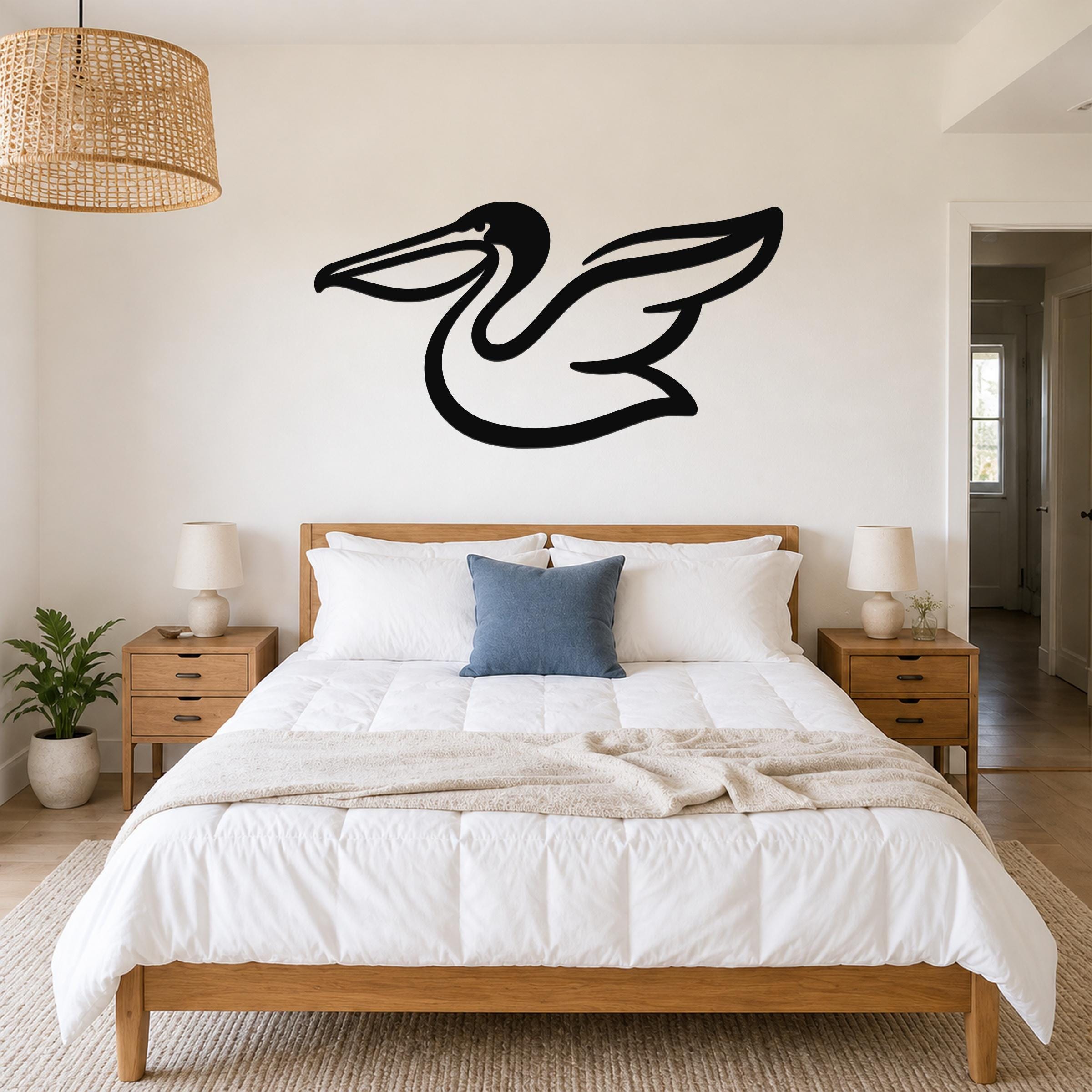 Black metal pelican wall art with a flowing silhouette, mounted above a wooden bed in a bright bedroom.
